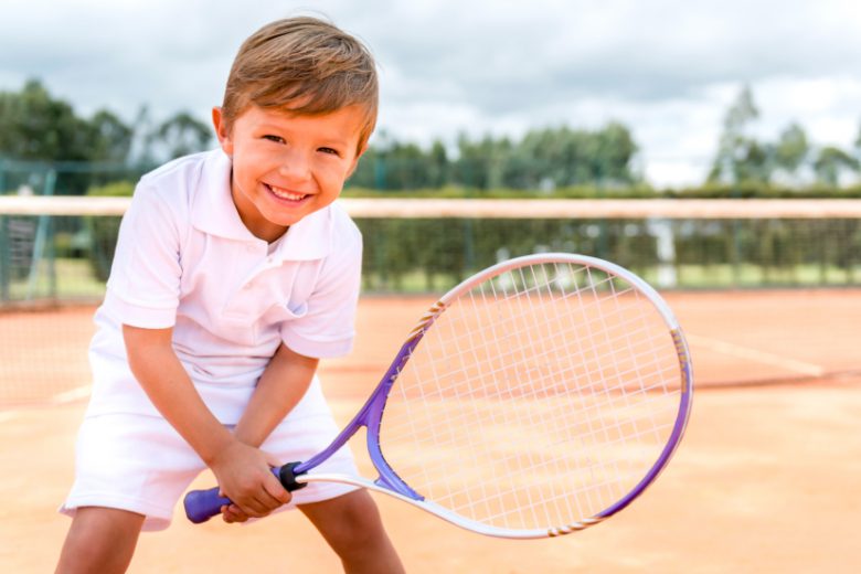 Boy playing tennis and looking very happy